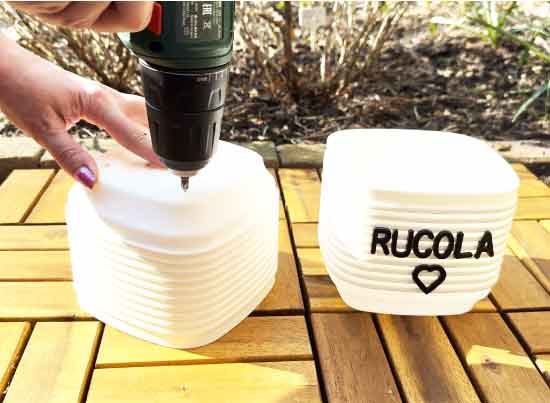 Ik boor drainagegaten in een witte pot voor rucola